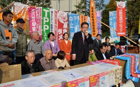 （写真）高齢者いじめはやめろと座り込む高齢者団体の人たちと日本共産党国会議員団。あいさつするのは小池晃副委員長（中央）＝１６日、東京都千代田区